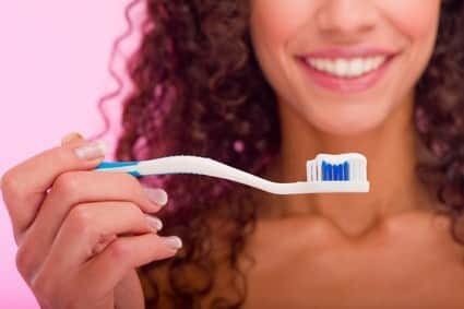 close up of a teeth brush and girl's smile behind