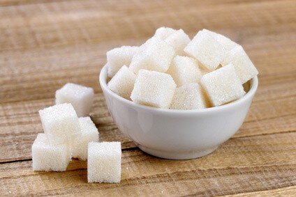 Sugar cubes in bowl on wooden table
