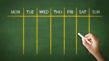 A person drawing and pointing at a Weekly Calendar Chalk Drawing